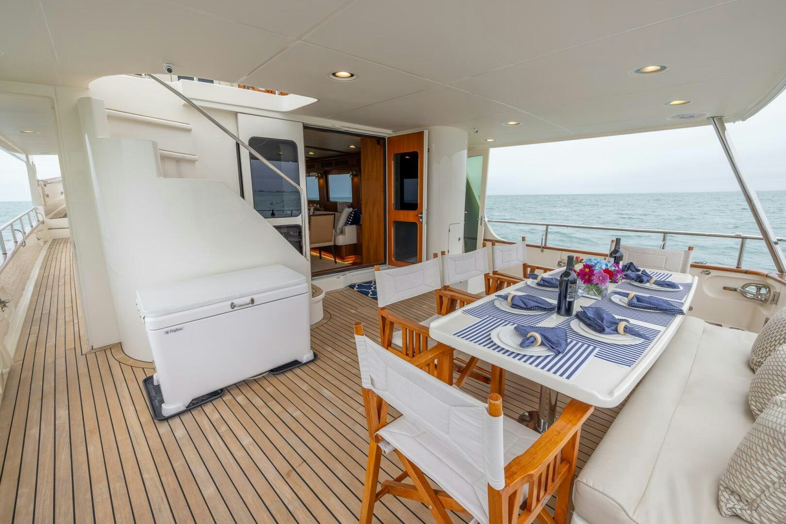 a large white dining table next to a large body of water aboard INDIGO Yacht for Sale