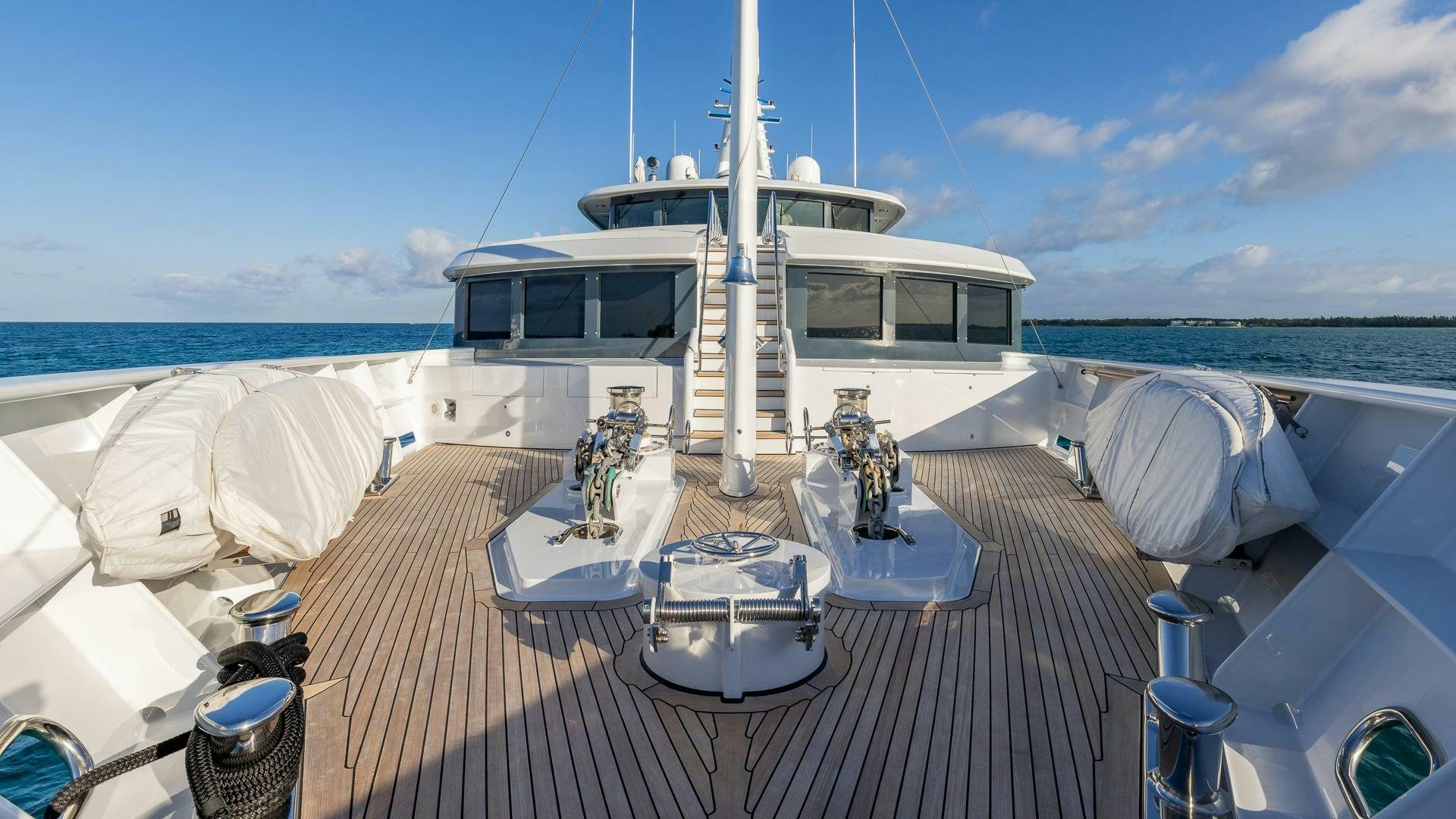 a deck with a table and chairs on it and a boat in the background aboard AMANTI Yacht for Sale