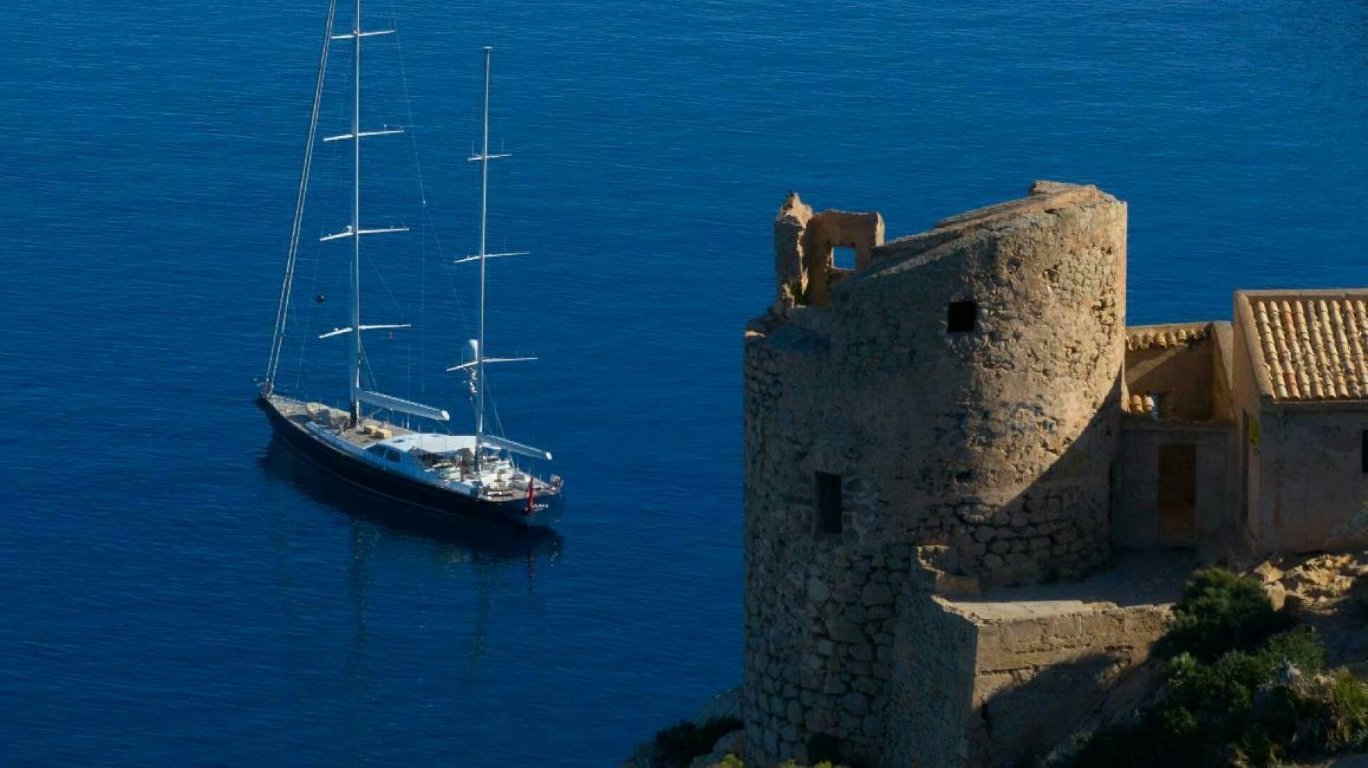 a goat on a cliff next to a boat aboard ANTARES Yacht for Sale