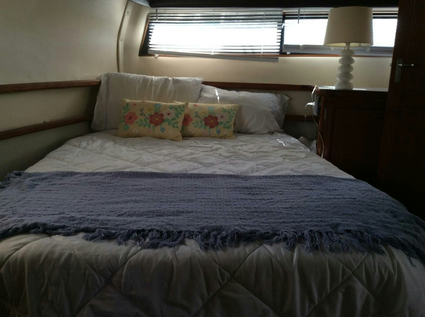 a bed with a blue comforter and pillows aboard TREES HOUSE Yacht for Sale