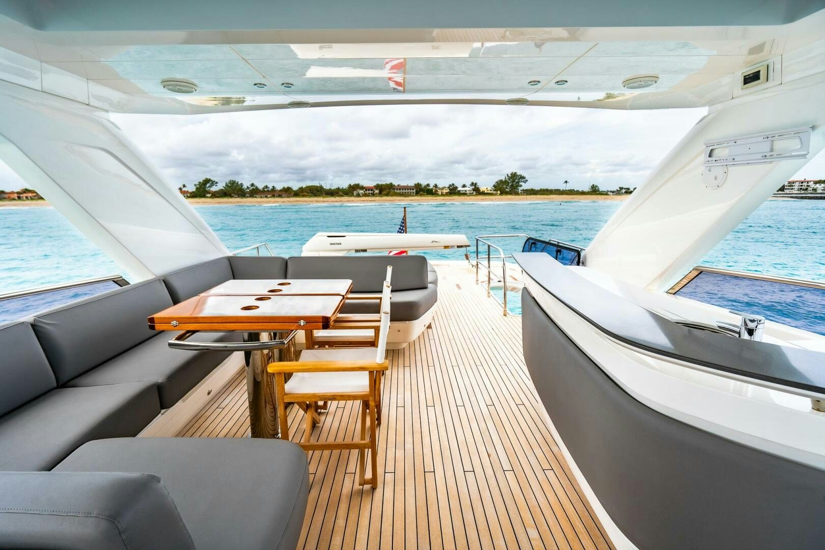 a deck with a table and chairs on it by a body of water aboard PERFECT MATCH Yacht for Sale