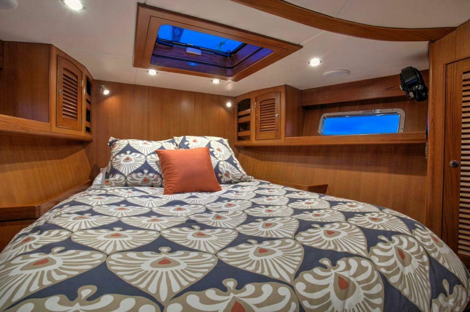 a bed with a blue comforter and red pillows aboard INDEPEPDENCE Yacht for Sale