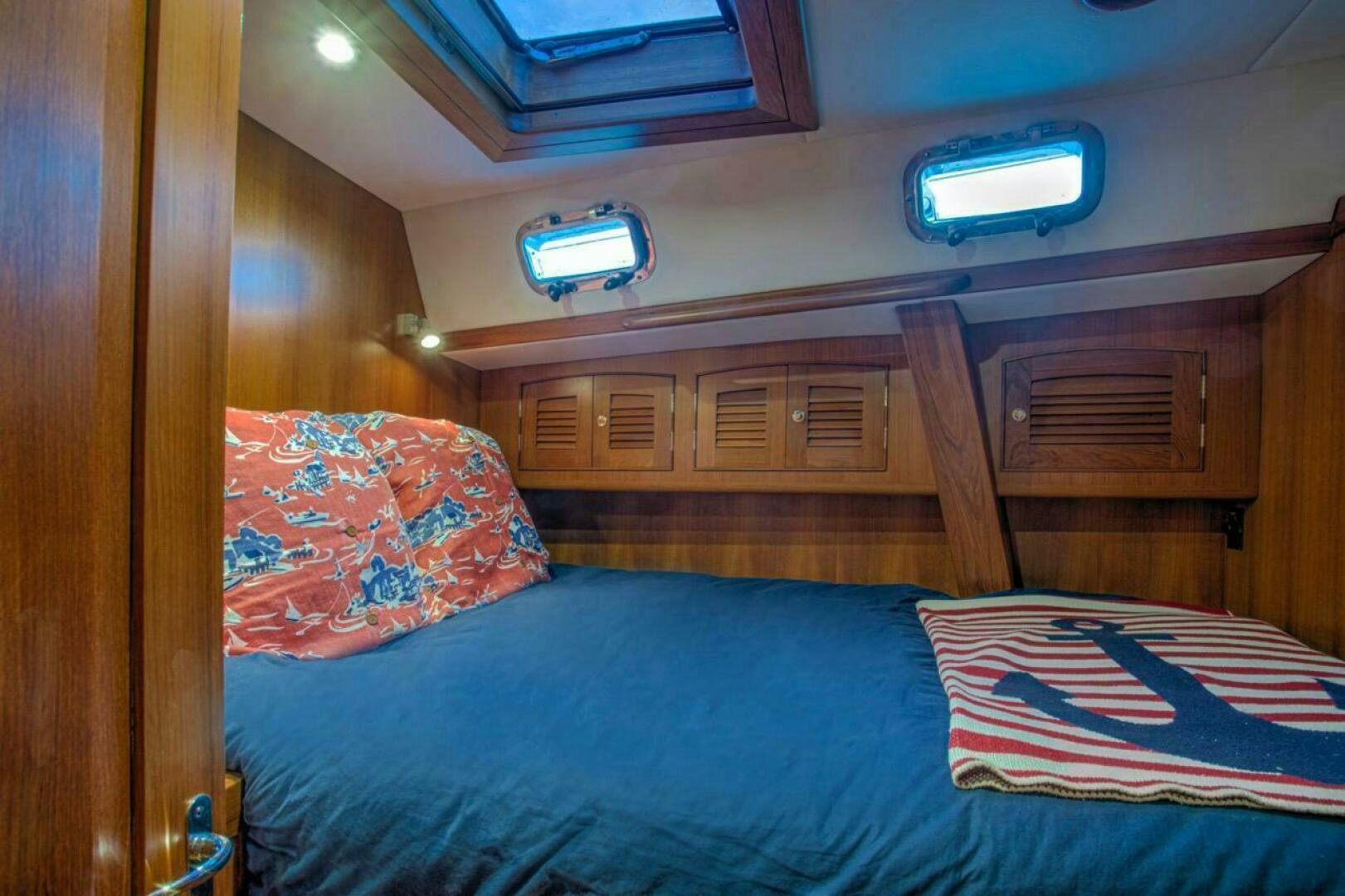 a bed with a blue comforter and a red and white pillow aboard INDEPEPDENCE Yacht for Sale