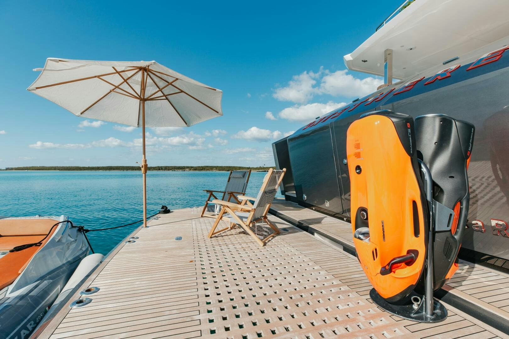 a boat on a dock with an umbrella and chairs on it aboard UNTETHERED Yacht for Sale