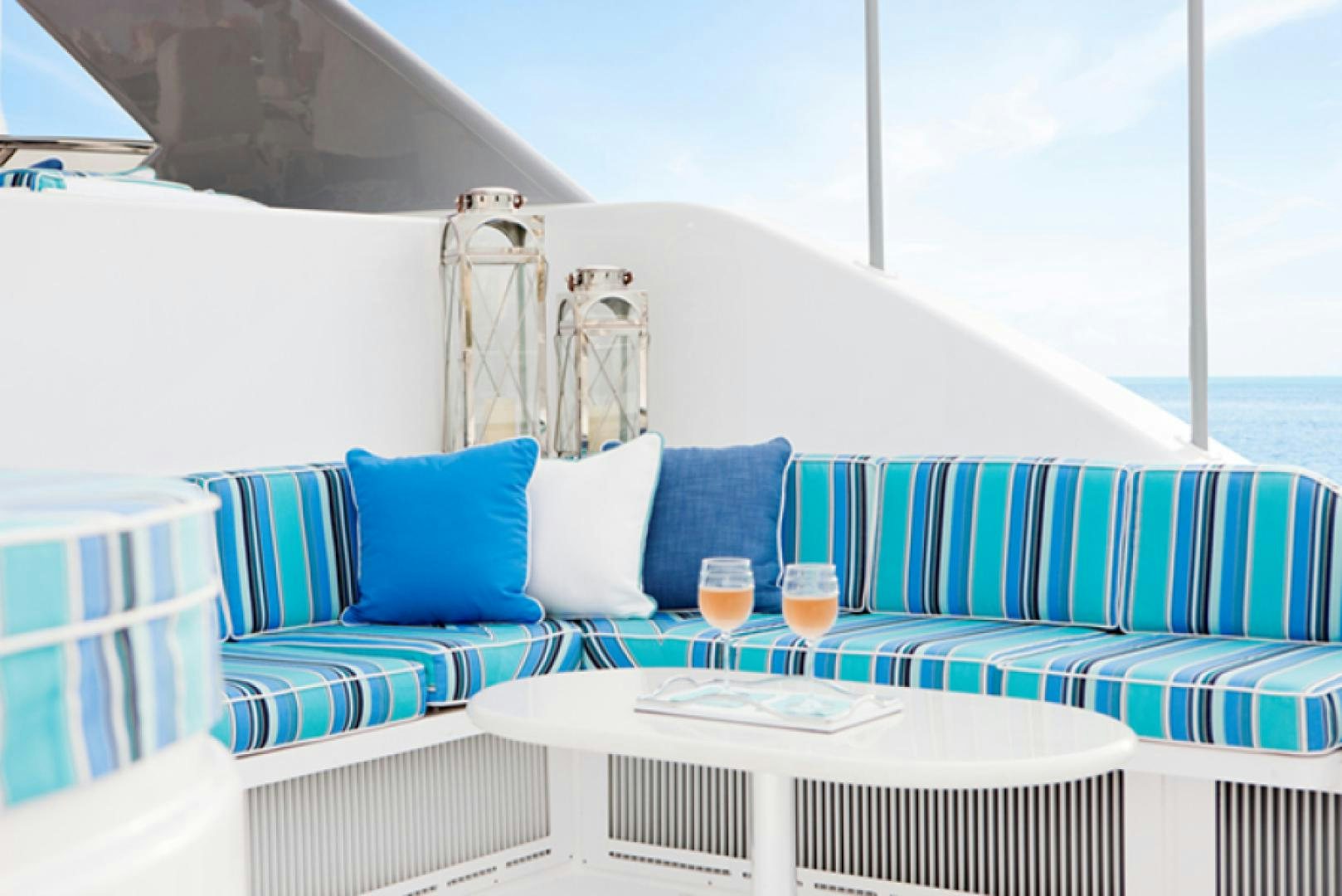 a white couch with blue pillows and white tablecloths aboard HANNAH Yacht for Sale