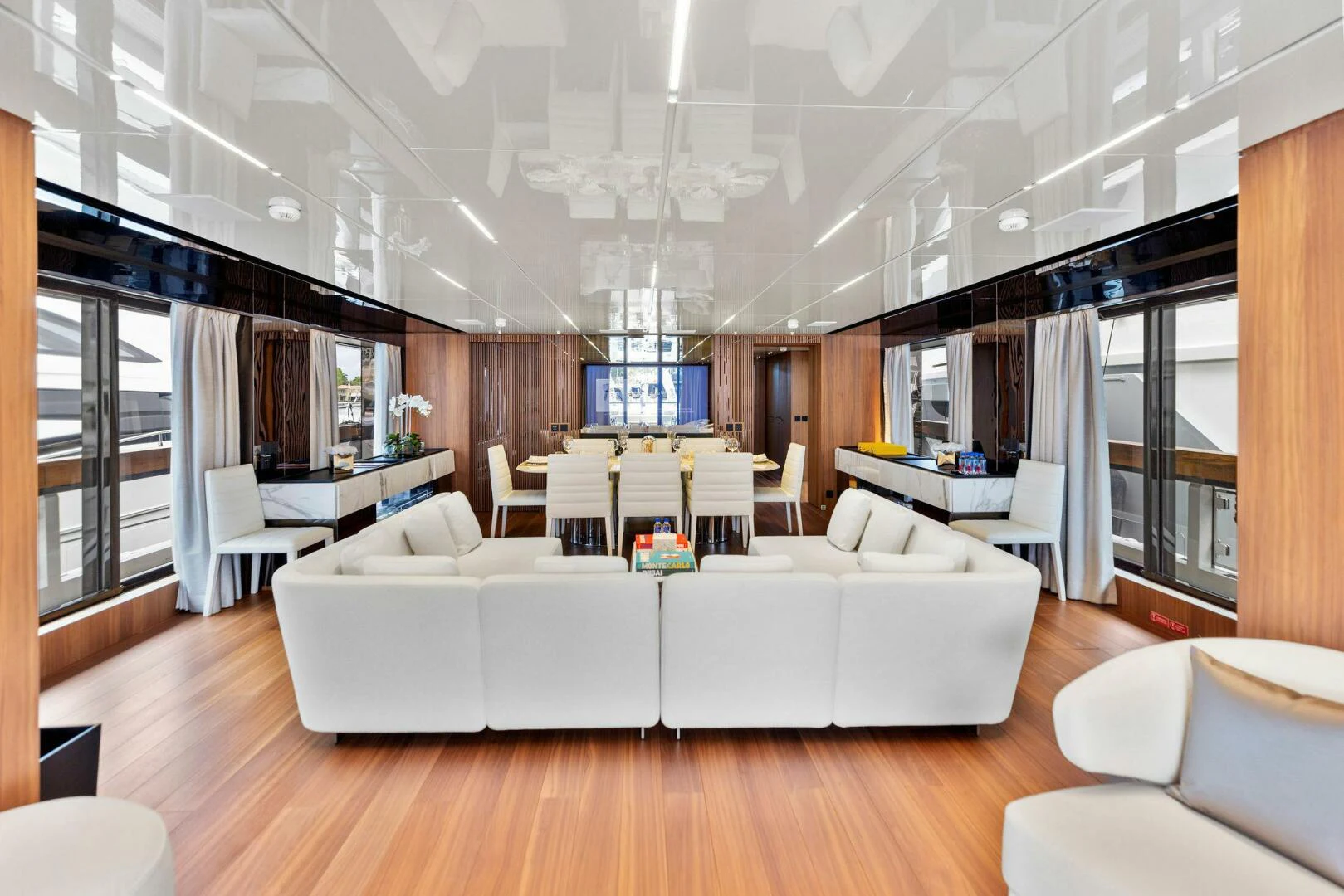 a living room with a large white couch and a large window aboard KAMAKASA Yacht for Sale