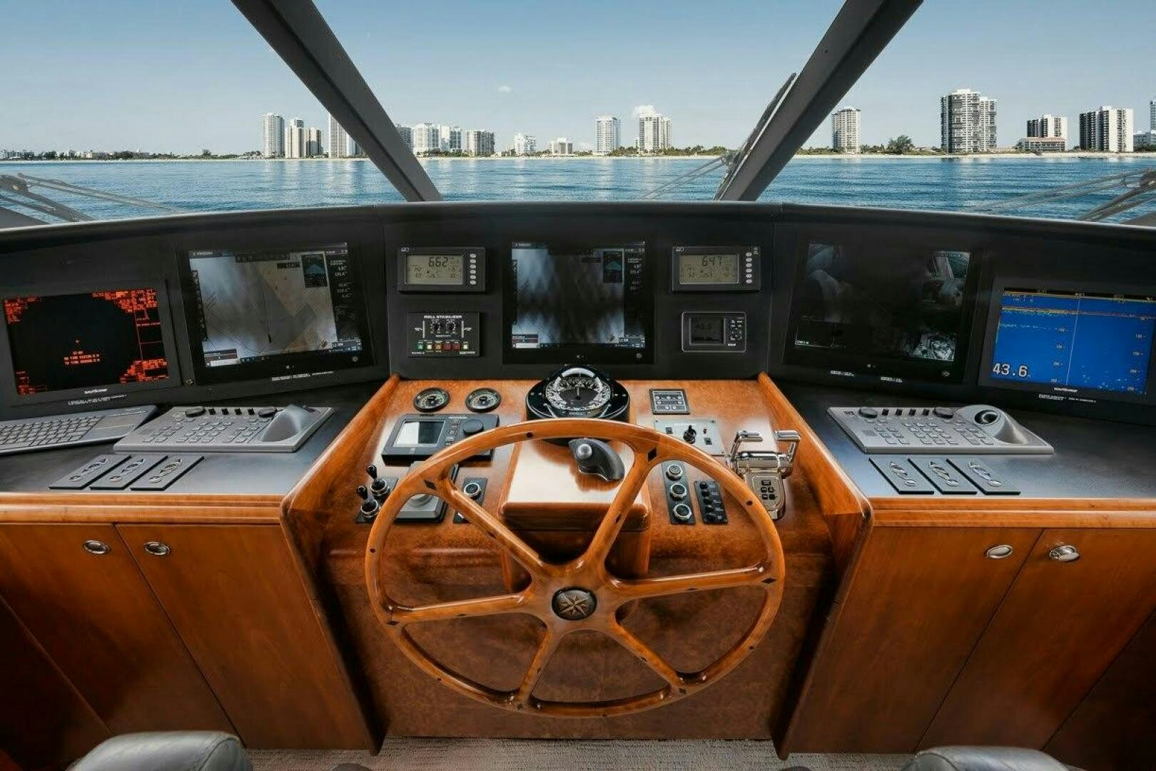 a wooden steering wheel on a wooden table with many screens aboard SLEEPOVER Yacht for Sale