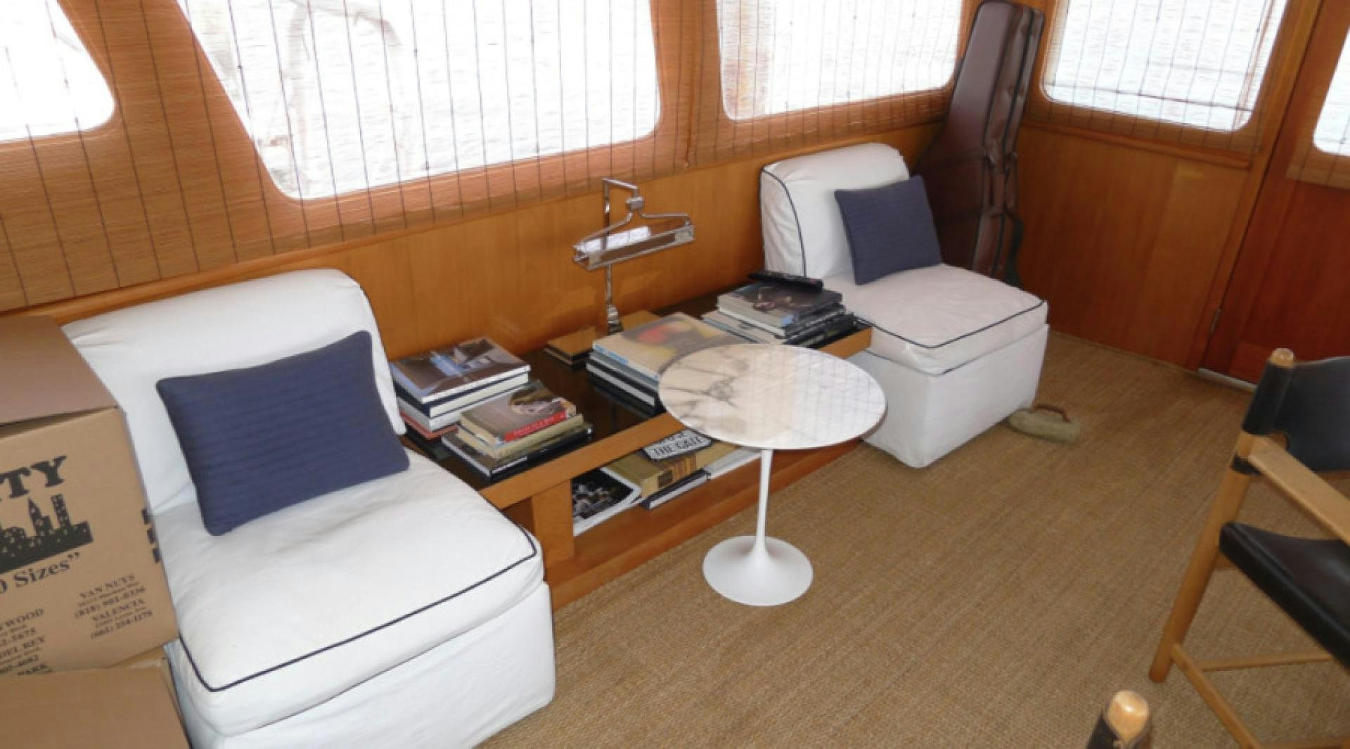 a room with a chair and a table with books on it aboard DAKOTA Yacht for Sale