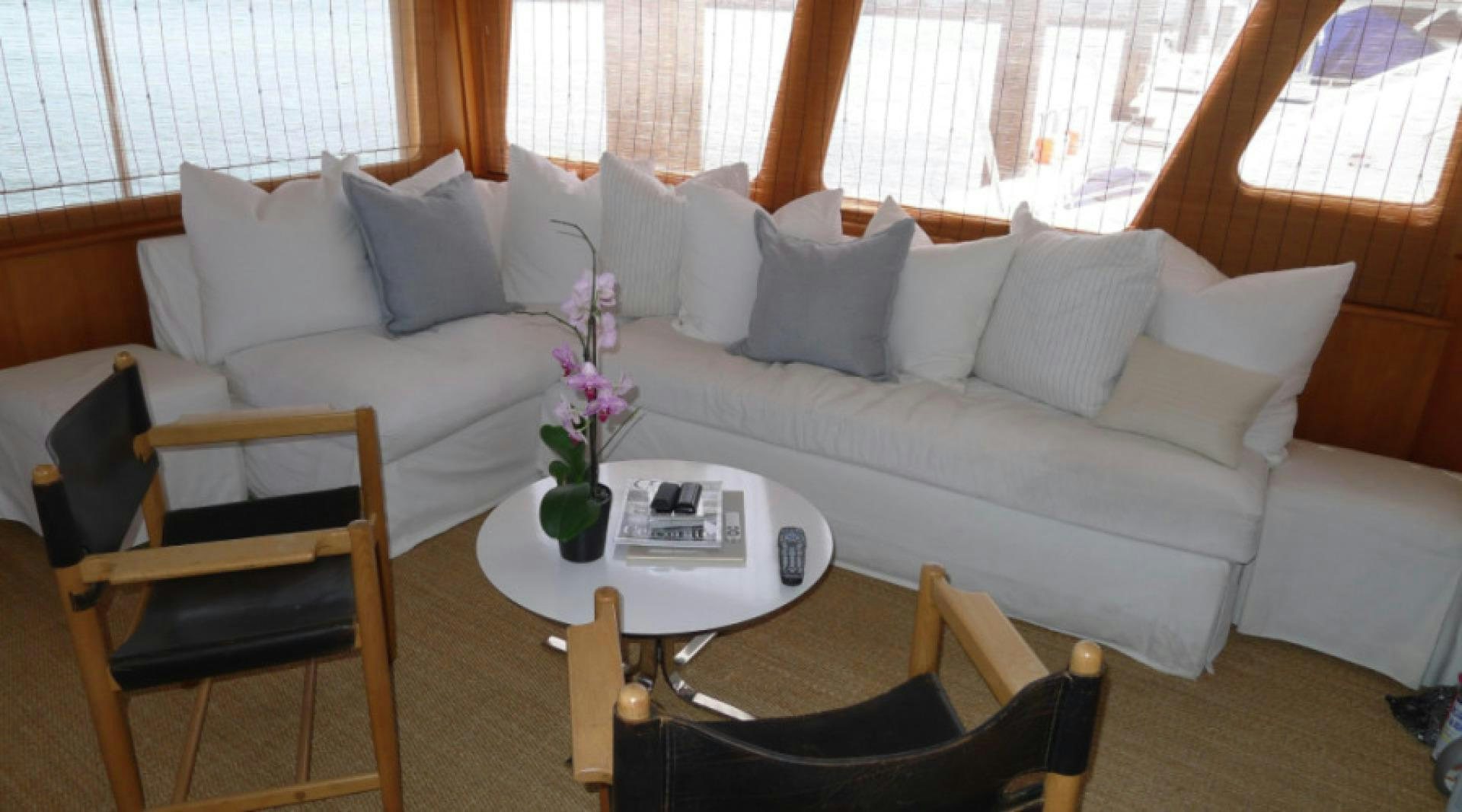 a white couch with a coffee table and chairs in a room with a window and curtains aboard DAKOTA Yacht for Sale