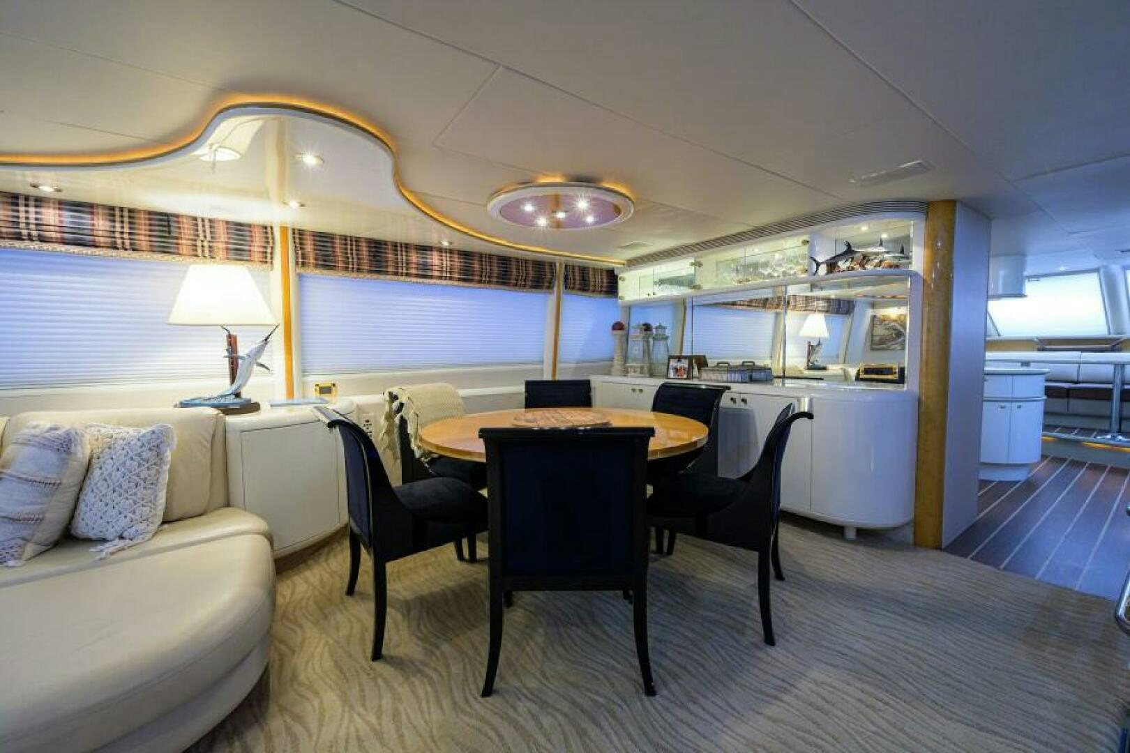 a dining table and chairs in a room with a couch and a window aboard 80' LAZZARA Yacht for Sale