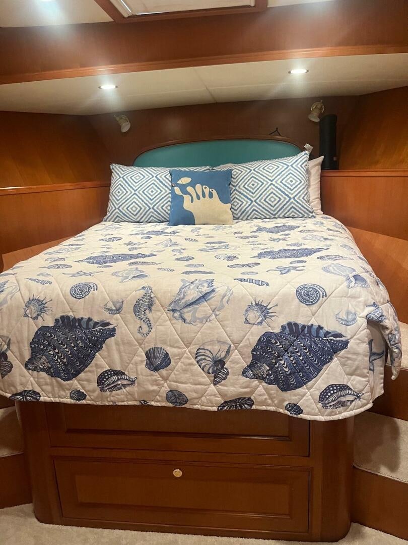 a bed with a blue and white comforter and pillows aboard MOODY BLUE Yacht for Sale