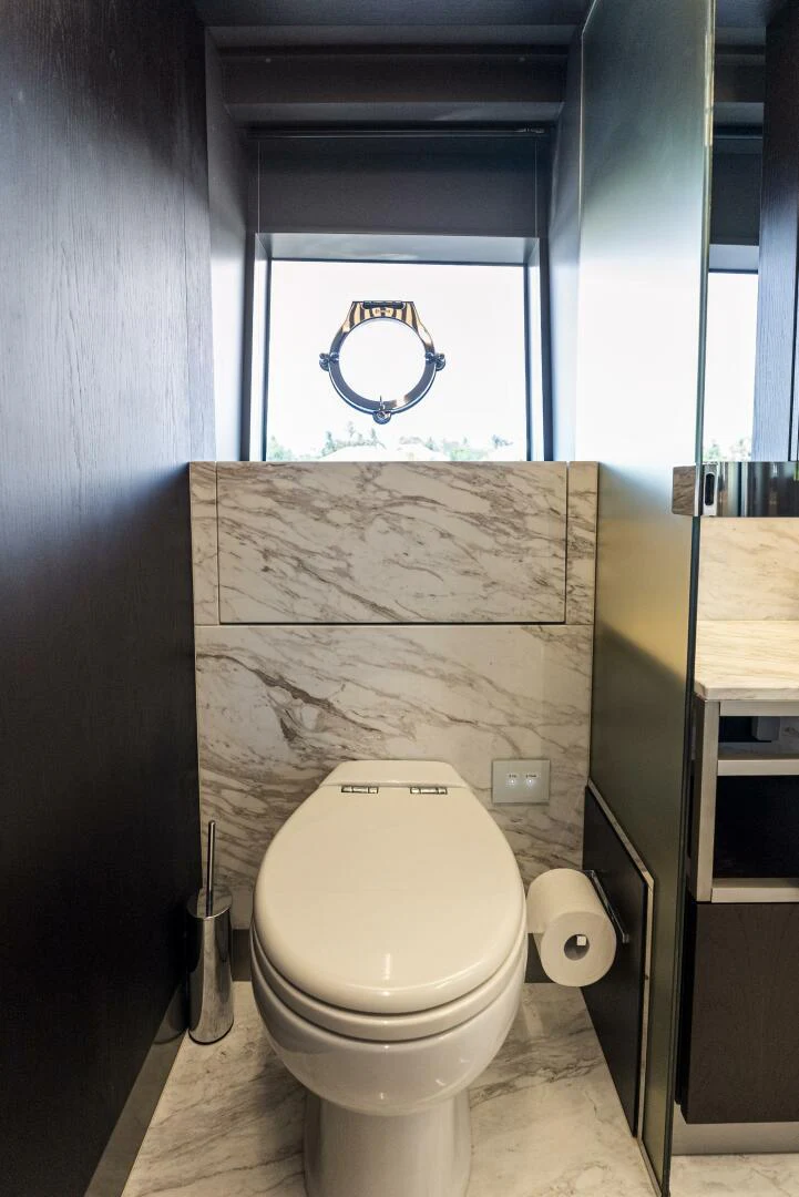 a bathroom with a toilet and a window aboard PINCH ME Yacht for Sale