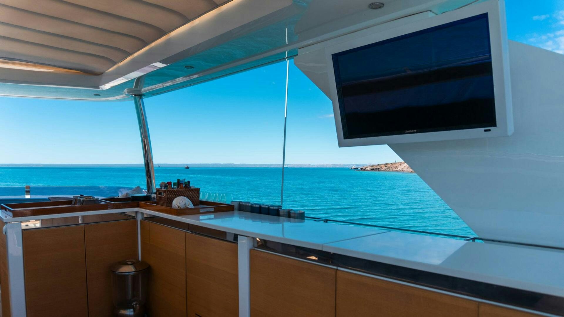 a large flat screen television on a white wall above a beach aboard SATORI Yacht for Sale