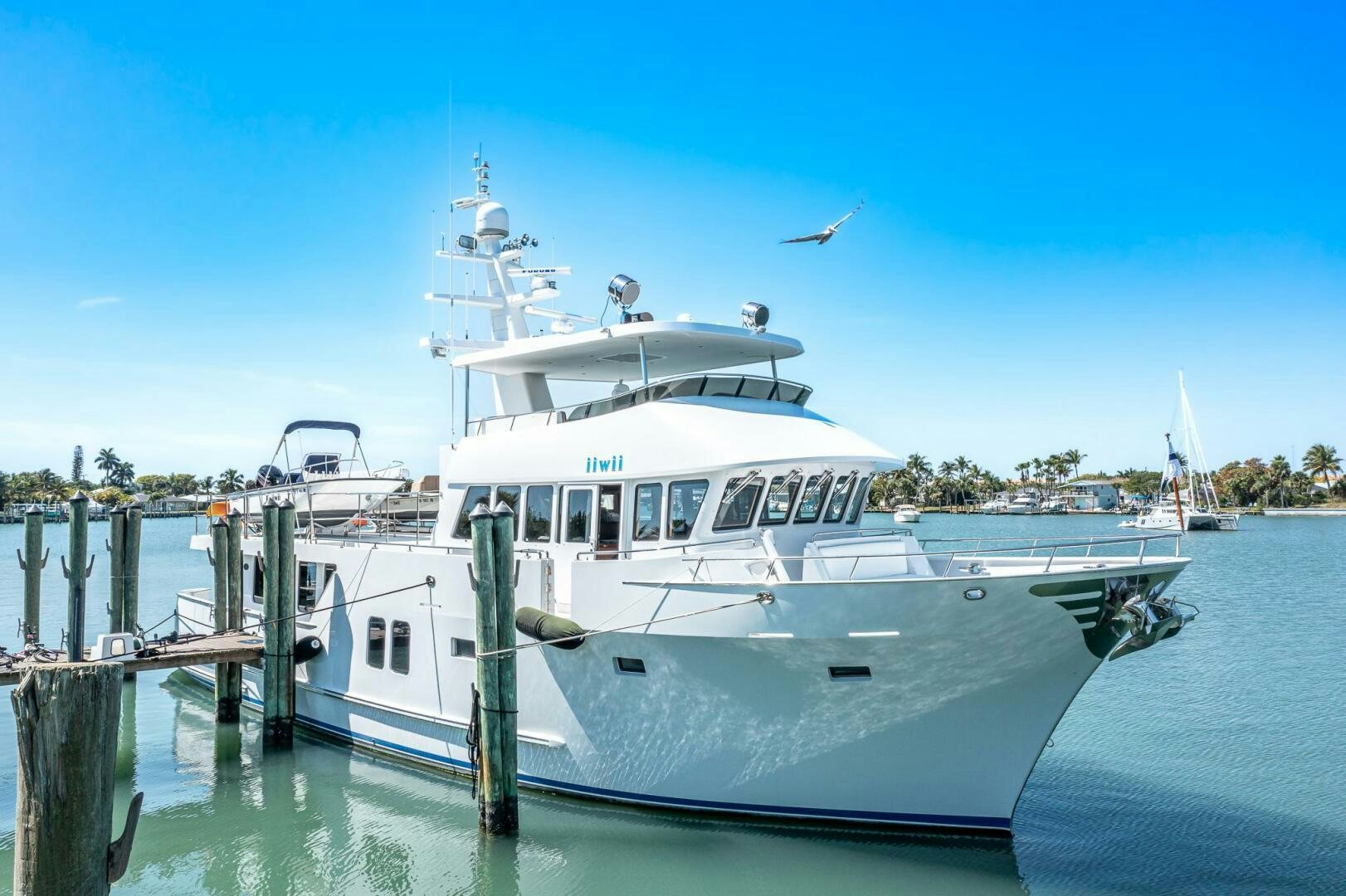 a white boat docked at a pier aboard IIWII Yacht for Sale
