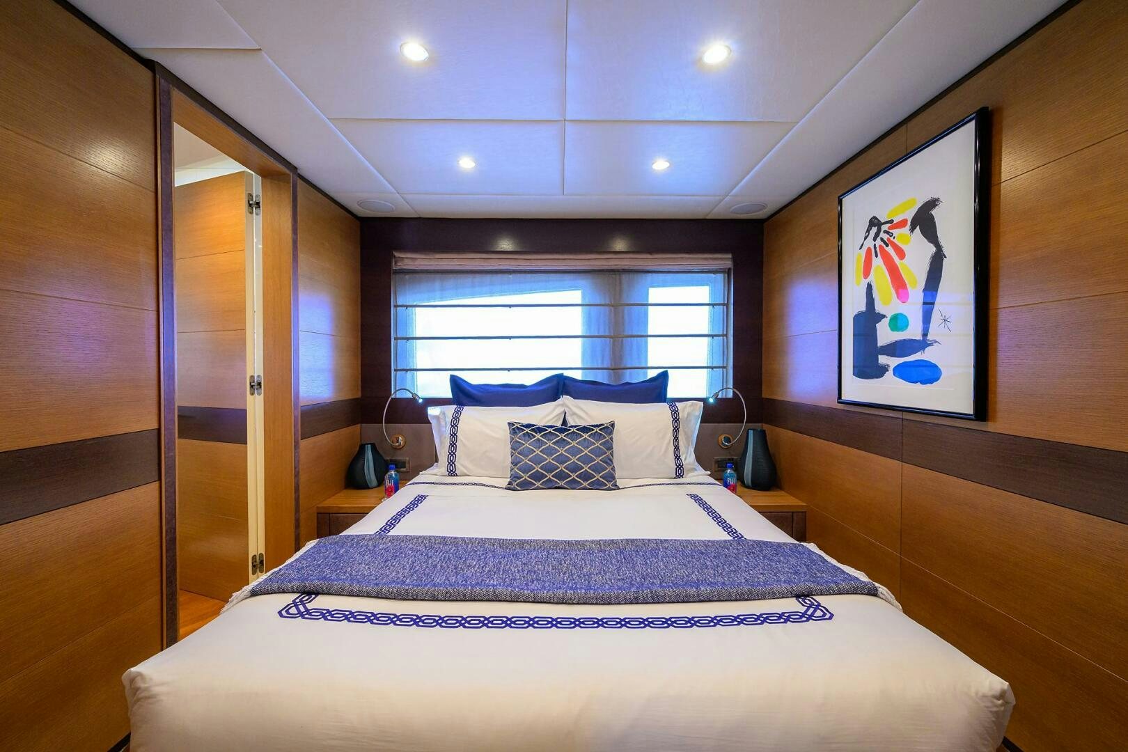 a bed with a blue and white comforter and a large window aboard KIMBERLIE Yacht for Sale