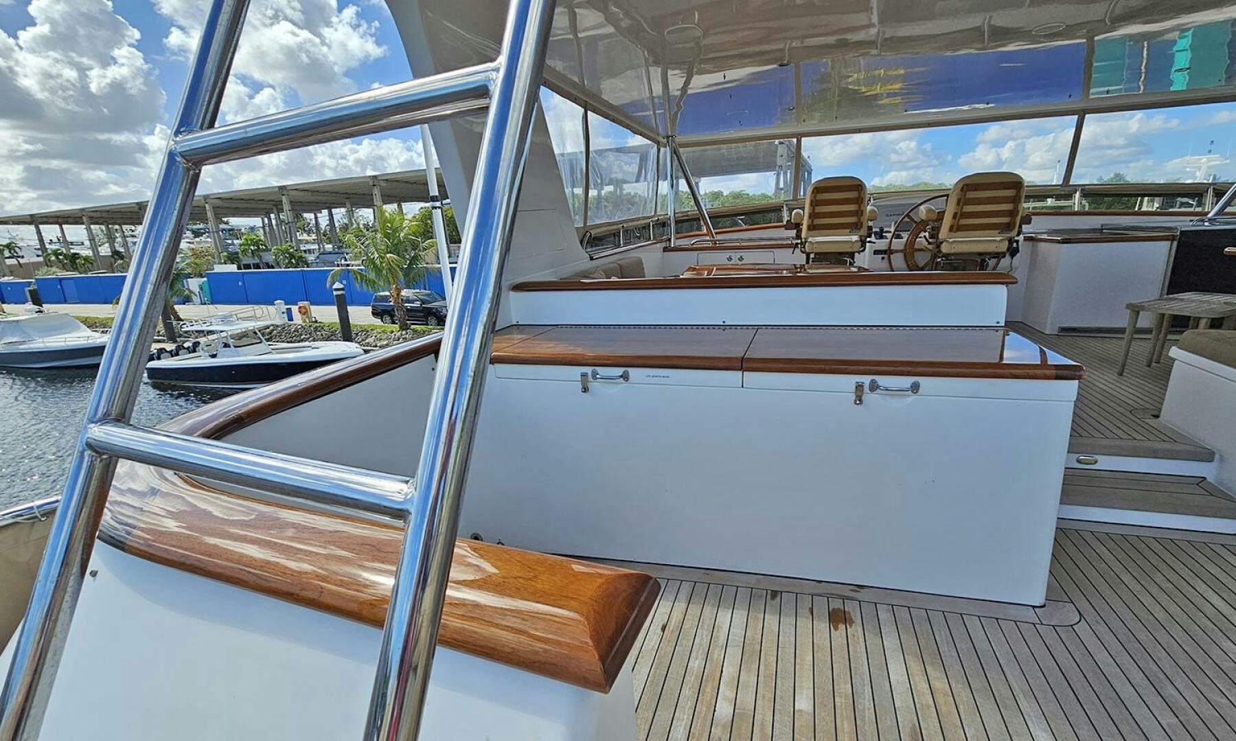 a large glass window with a wood deck and a deck with chairs and a pool and trees and aboard MY KIMBERLY Yacht for Sale