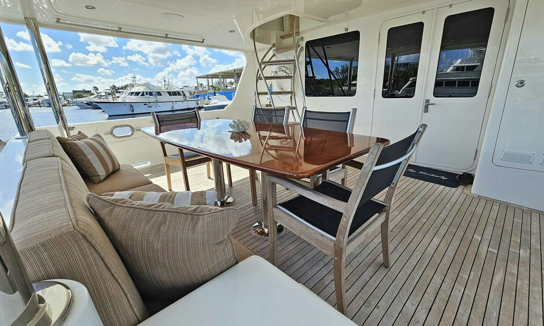 a deck with a table chairs and a window aboard MY KIMBERLY Yacht for Sale