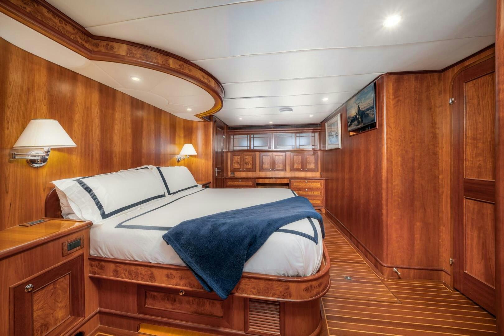 a bedroom with a bed and a wood cabinet aboard BAD-LAD Yacht for Sale