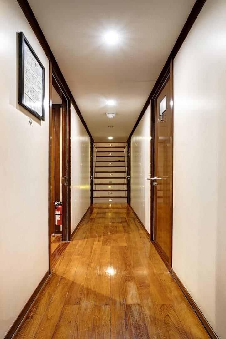 a hallway with a wood floor and a door with a mirror on the wall aboard SWEET CAROLINE Yacht for Sale