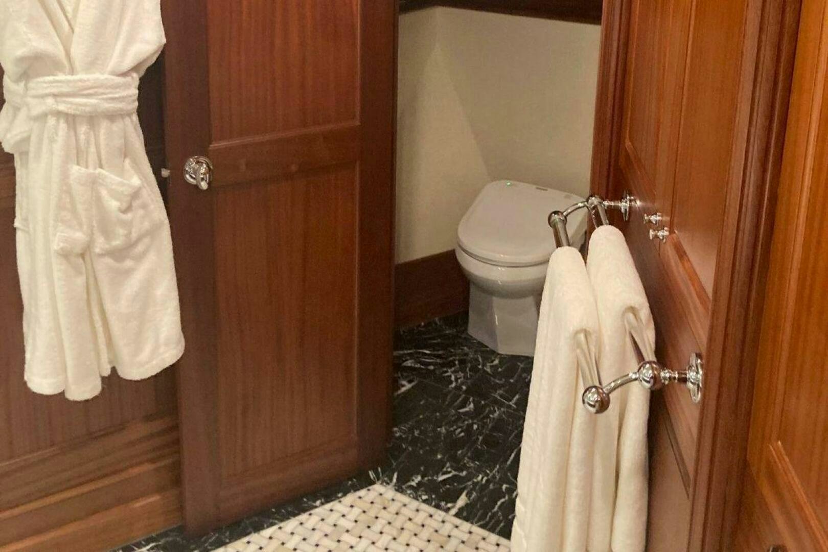 a bathroom with a toilet and a robe aboard ALLSEAS Yacht for Sale