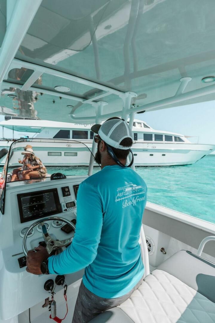a person in a uniform holding a steering wheel on a boat aboard BEACHFRONT Yacht for Sale