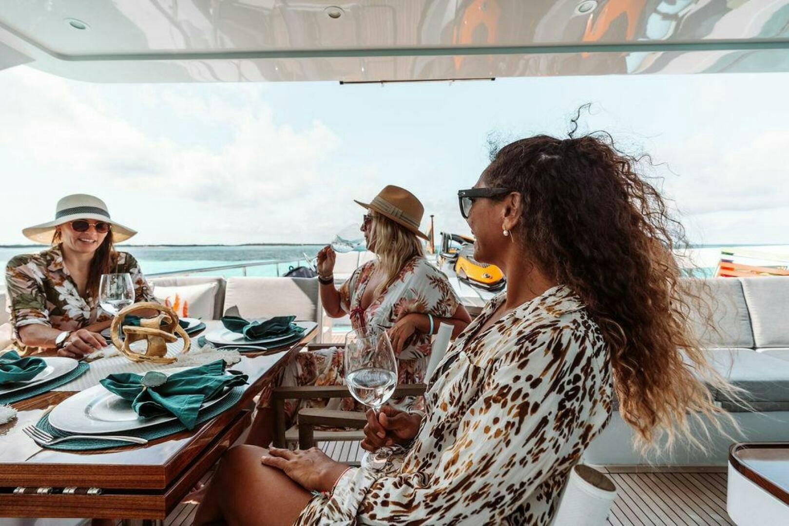 a group of people sitting at a table with food and drinks aboard BEACHFRONT Yacht for Sale