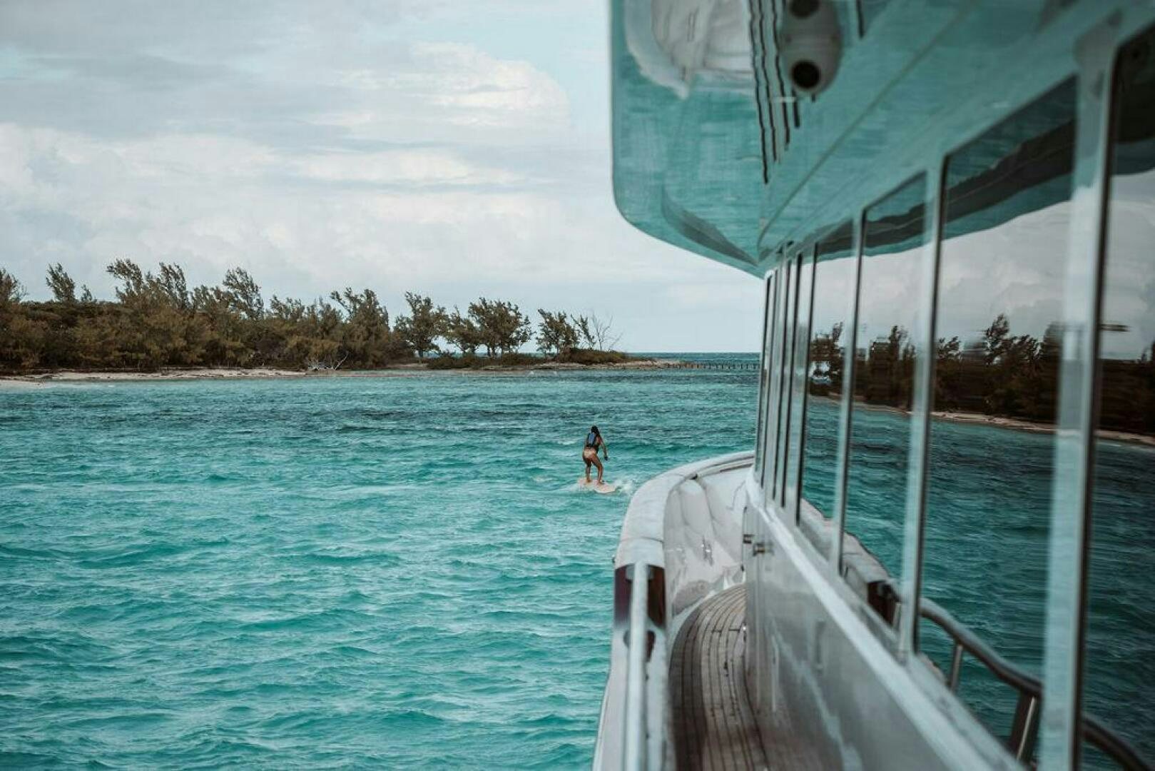 a person standing in the water next to a boat aboard BEACHFRONT Yacht for Sale