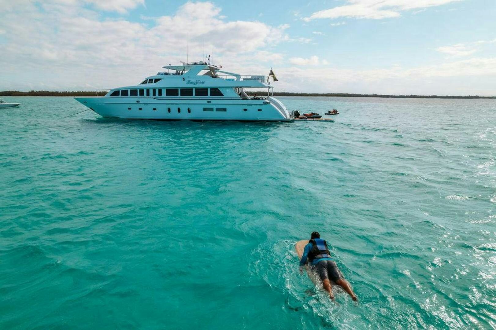 a person and a dog in the water with a boat in the background aboard BEACHFRONT Yacht for Sale