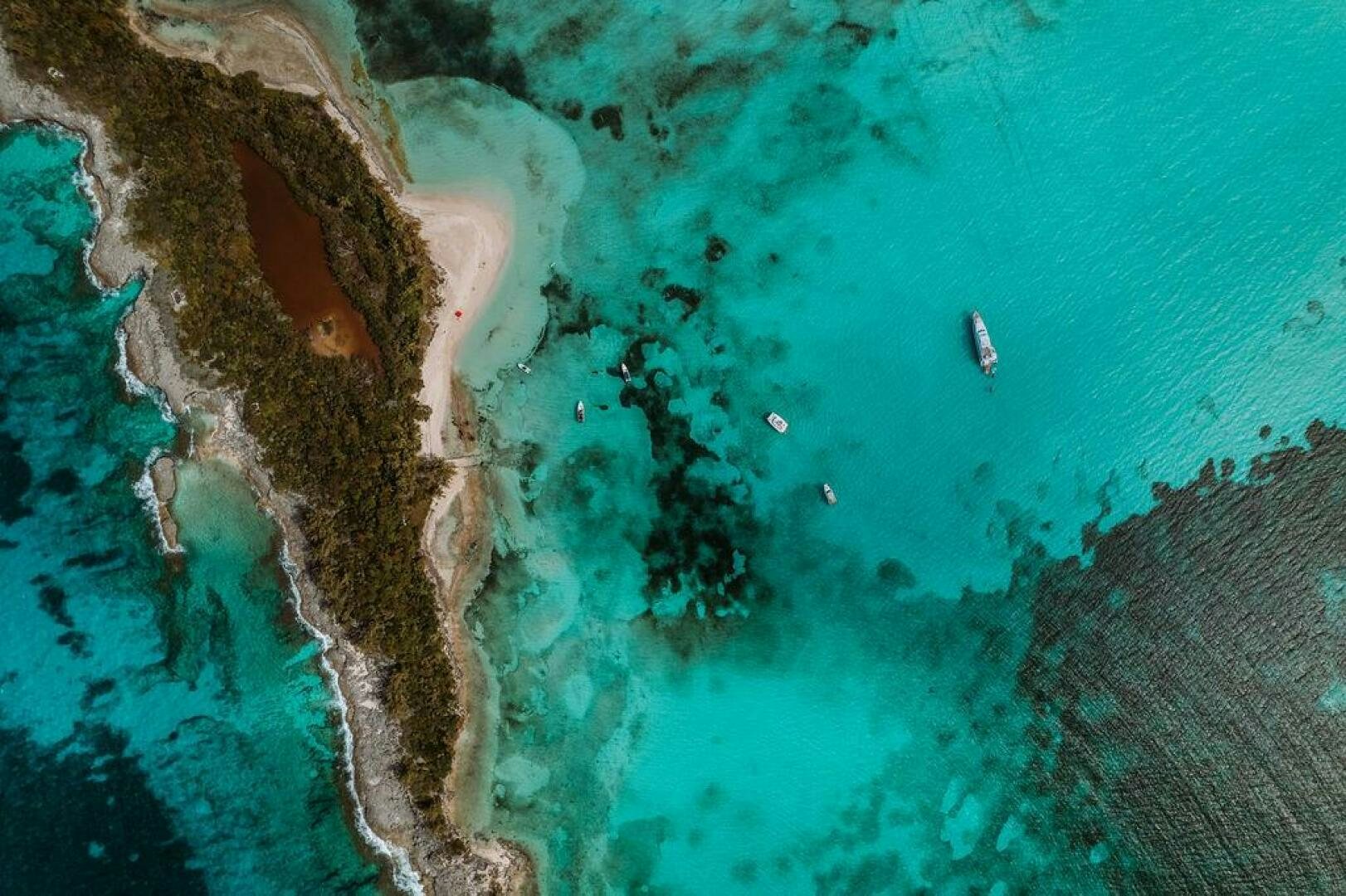 a body of water with a rocky shore and a boat in the water aboard BEACHFRONT Yacht for Sale