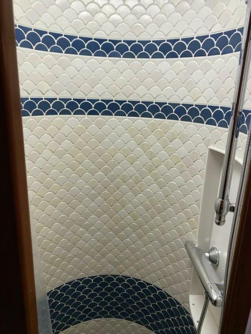 a bathroom with a blue tiled shower curtain aboard PRECIOUS CARGO Yacht for Sale