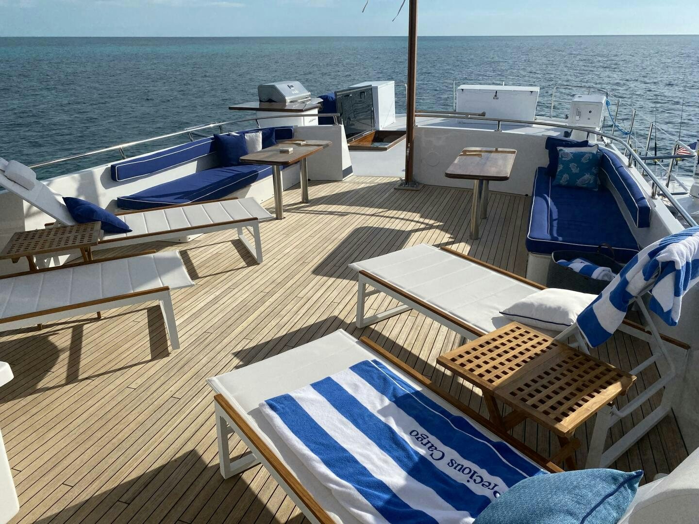 a deck with chairs and tables on it by the water aboard PRECIOUS CARGO Yacht for Sale