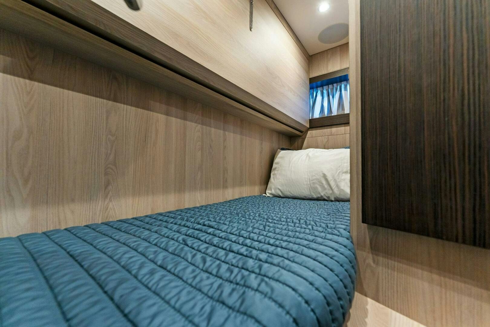 a bed with a blue sheet aboard LIMITLESS Yacht for Sale
