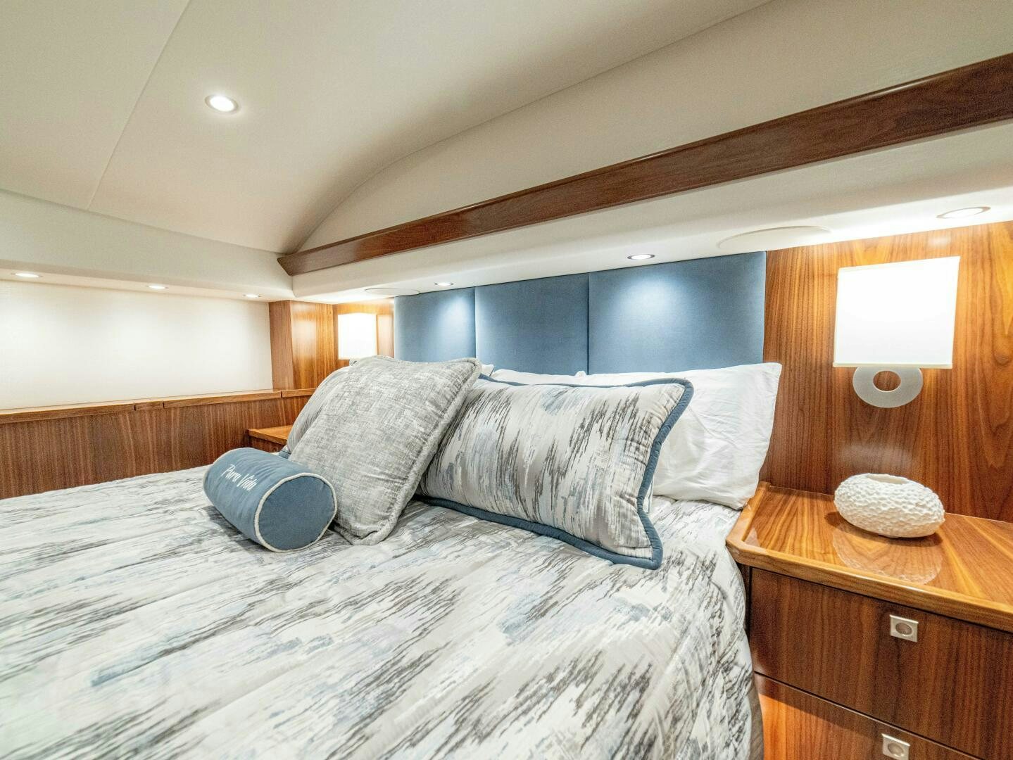 a bed with a blue and white bed spread aboard PURA VIDA Yacht for Sale