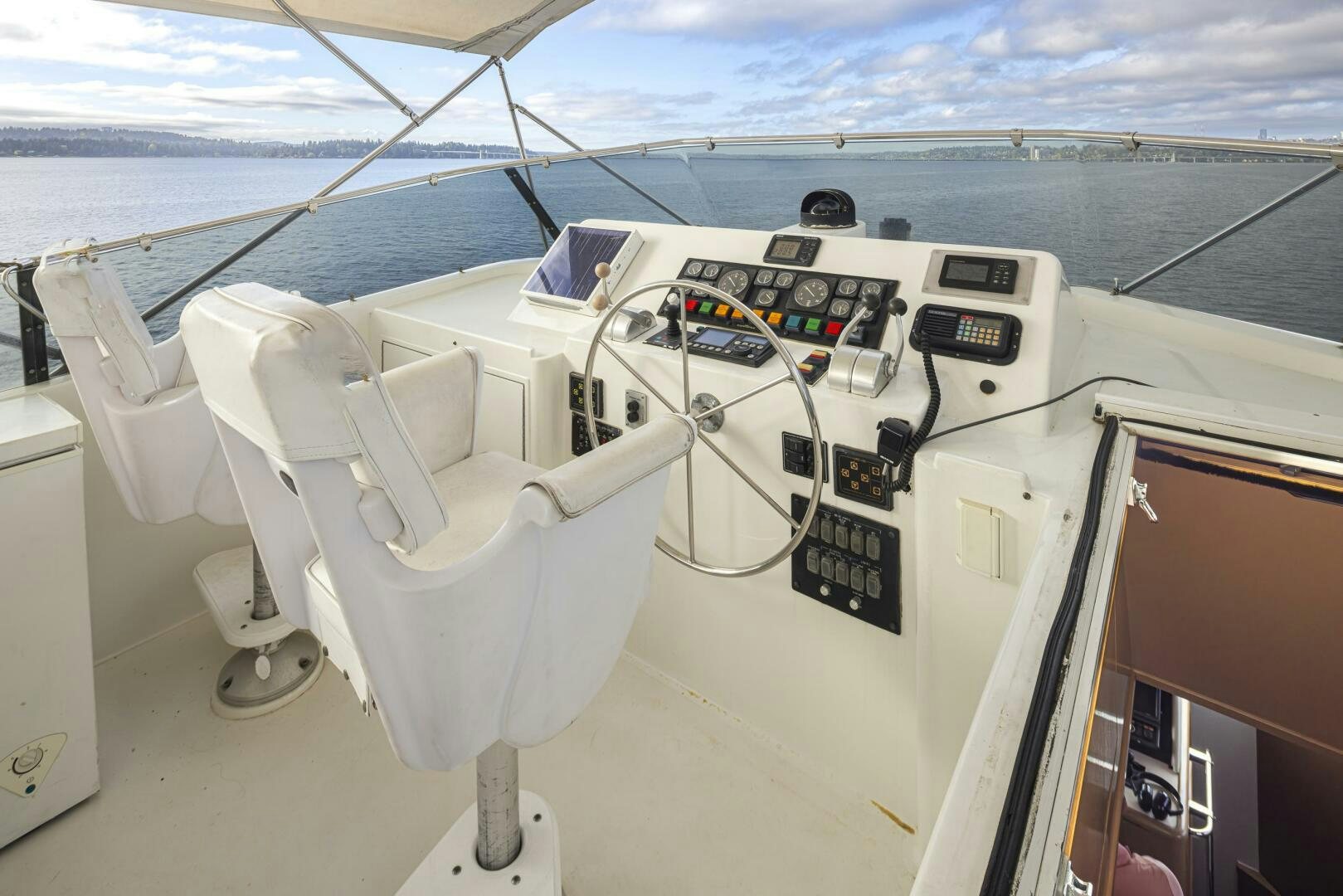 a white boat with a seat and steering wheel and a window with a view of the ocean and aboard LISA SEA I Yacht for Sale