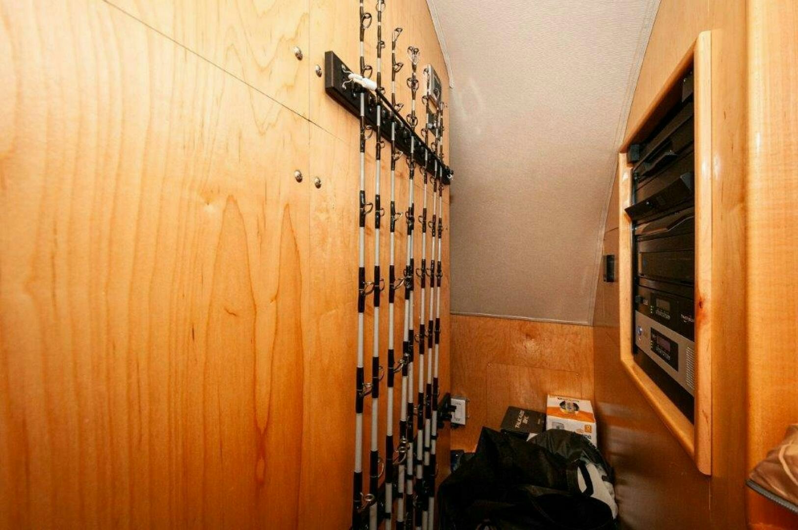 a room with a wood floor and a closet with a black and white ladder and a black box aboard GUNNSLINGER Yacht for Sale