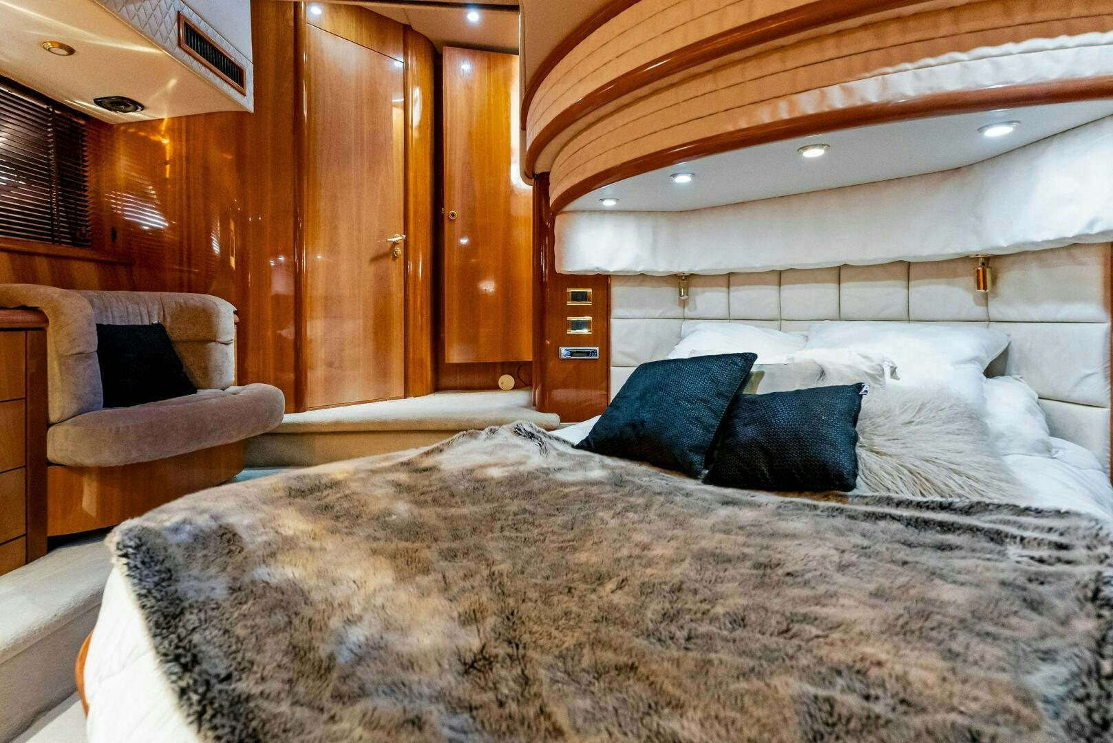 a bed with a chair and a couch in a room aboard GAMBLER Yacht for Sale