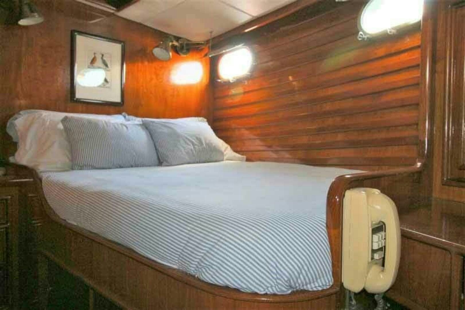 a bed with a white sheet and a wooden wall aboard KOKOMO VI Yacht for Sale