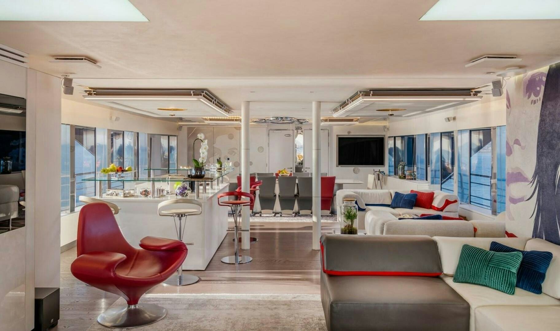 a living room with a red chair and a table aboard JOY ME Yacht for Sale