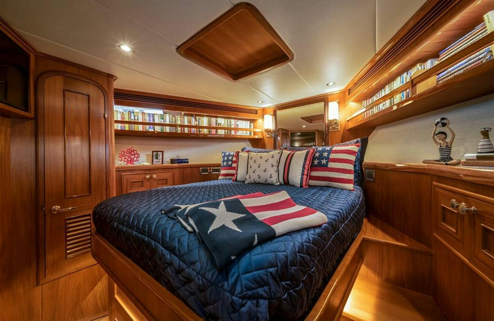 a bed with a blue blanket and pillows in a room with wood cabinets aboard JULIANNE Yacht for Sale