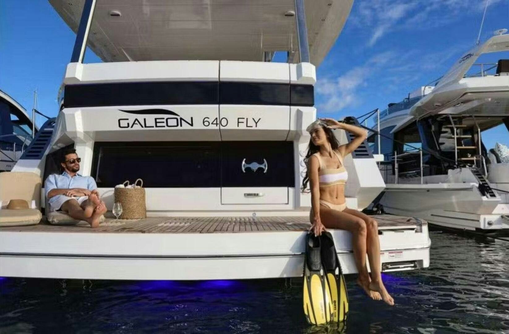 a woman standing on a boat with a man sitting on the side aboard TRIPLE T Yacht for Sale
