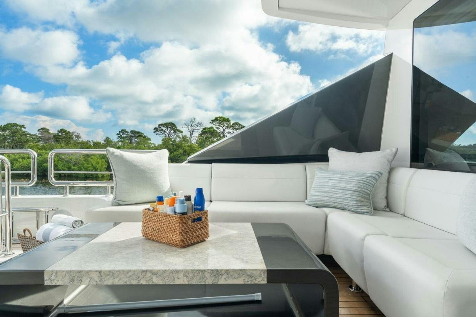 a white couch with a table and a white sofa in a room with a large window and blue aboard LADY G Yacht for Sale
