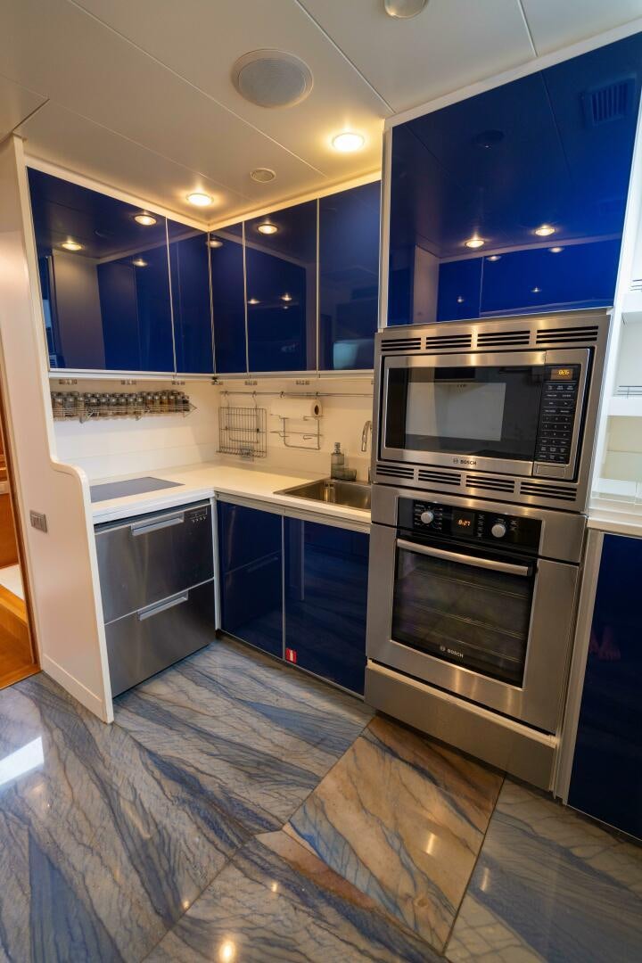 a kitchen with blue cabinets aboard LOSAND Yacht for Sale