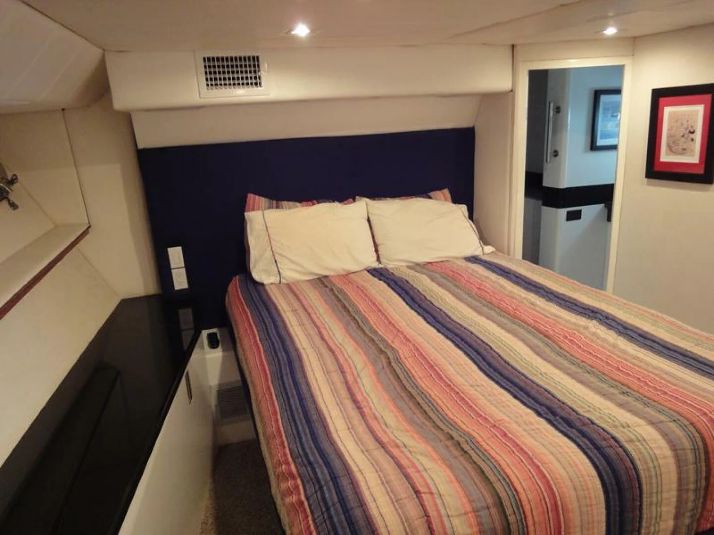 a bed with a blue and white striped blanket aboard PIER PRESSURE Yacht for Sale