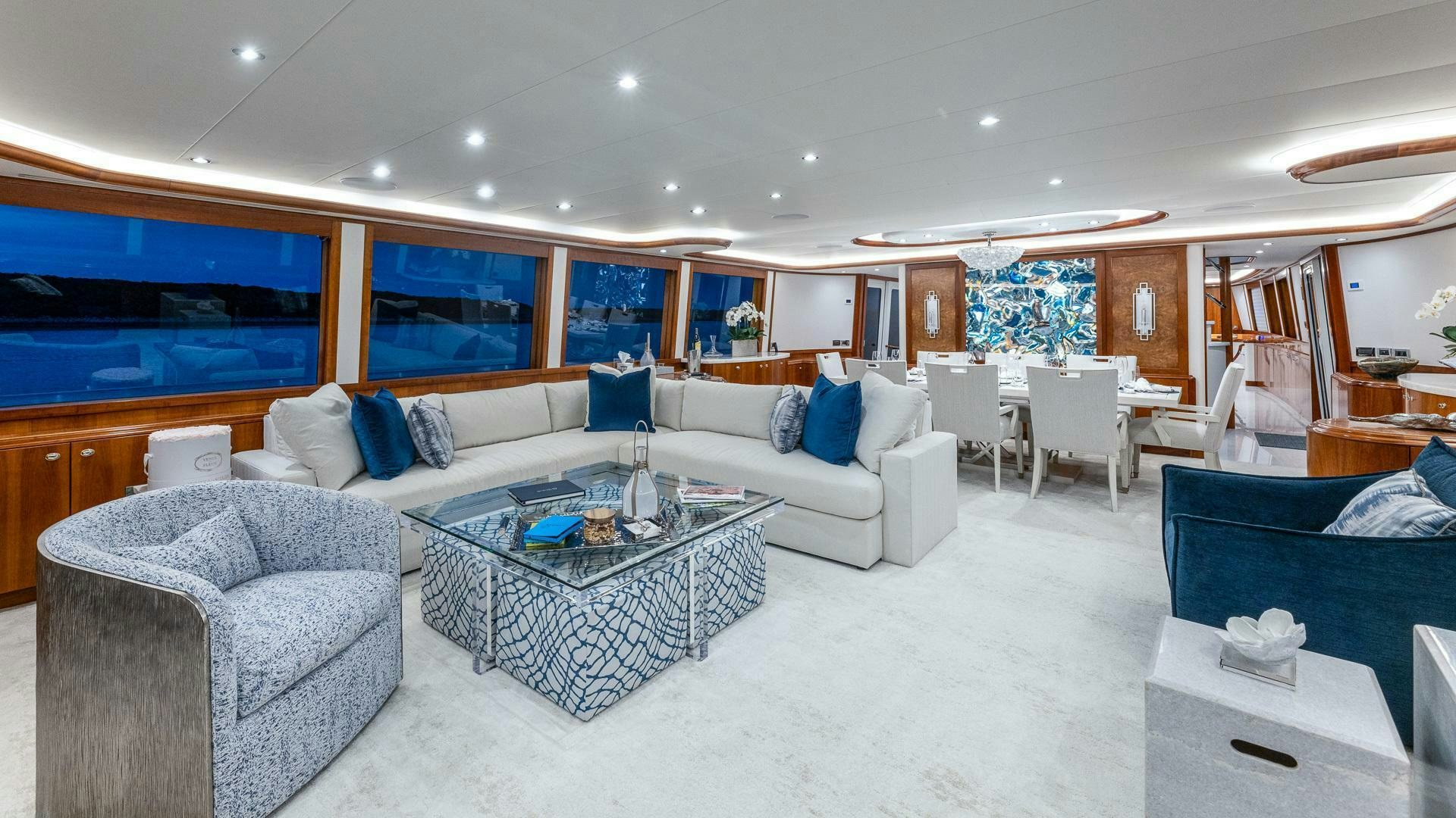 a living room with a large blue couch and a large window aboard NO SHORTCUTS Yacht for Sale