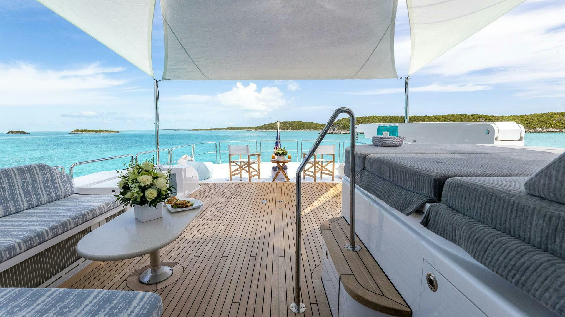 a balcony with a table and chairs on the deck aboard NO SHORTCUTS Yacht for Sale