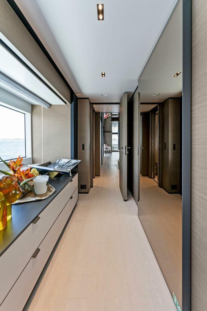 a long narrow hallway with a desk and a window aboard FAMILIA Yacht for Sale