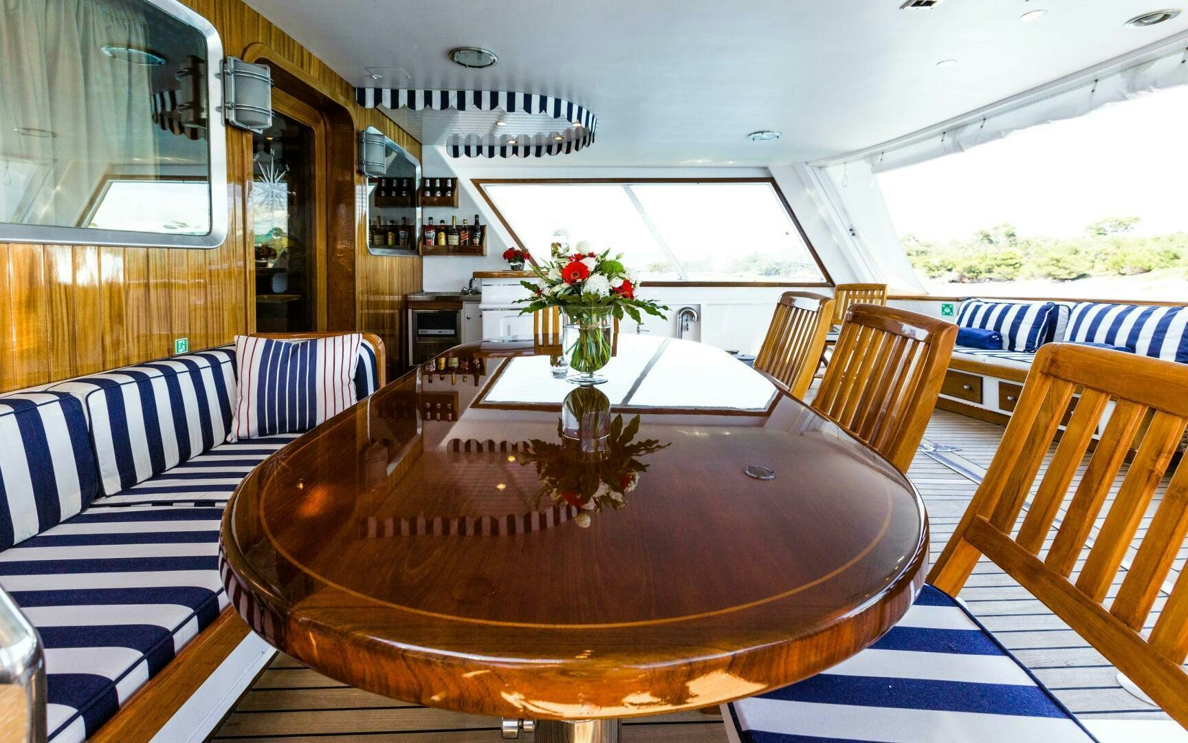 a wooden table with chairs and a couch in a room with a window aboard STAR OF THE SEA Yacht for Sale