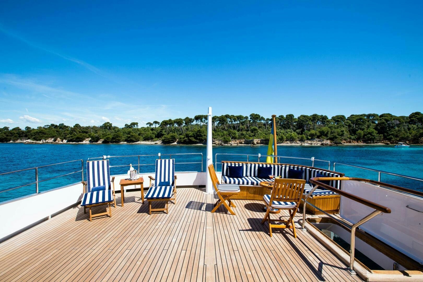 a deck with chairs and tables on it by a body of water aboard STAR OF THE SEA Yacht for Sale