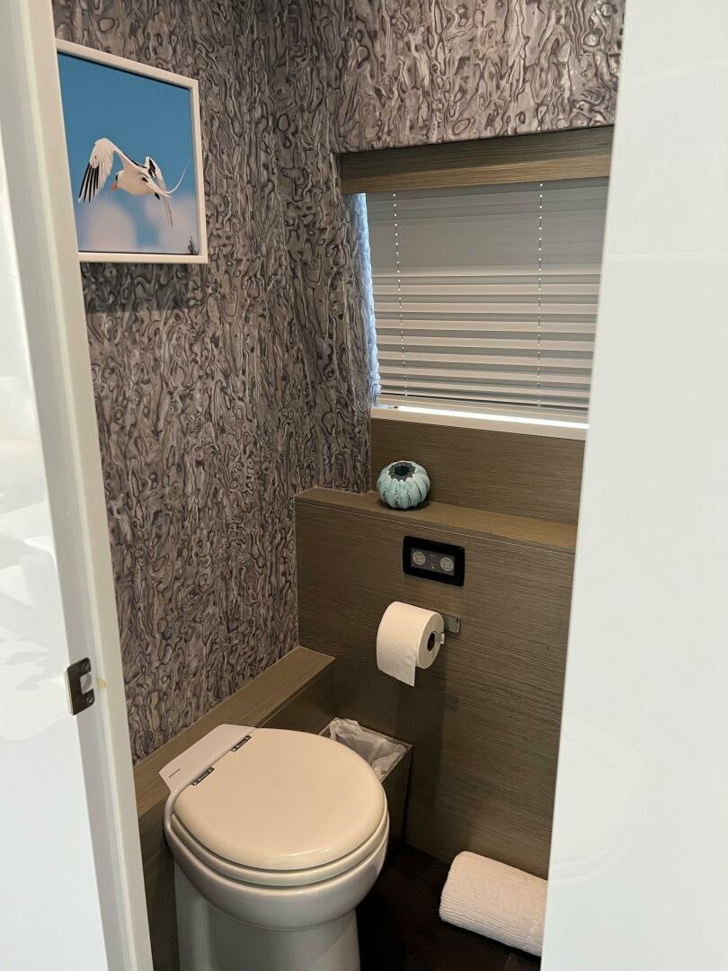 a bathroom with a toilet and a painting on the wall aboard HAPPY HEART Yacht for Sale