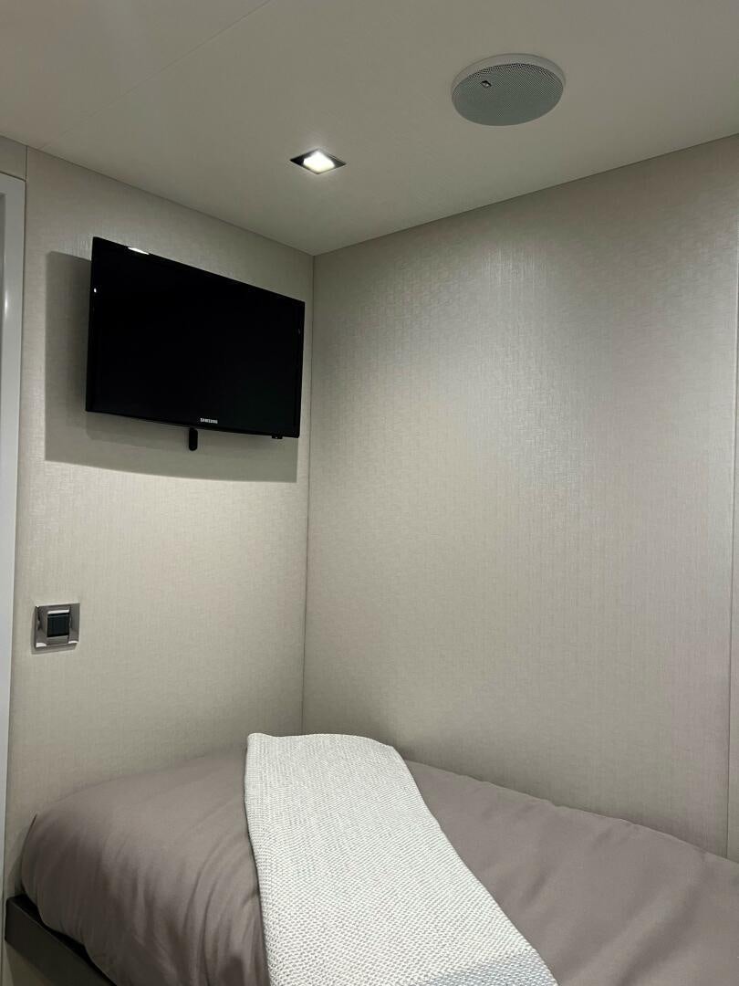 a bed with a television on the wall aboard HAPPY HEART Yacht for Sale